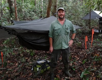 Dr. Emrick stands in a remote field camp in the Amazon jungle