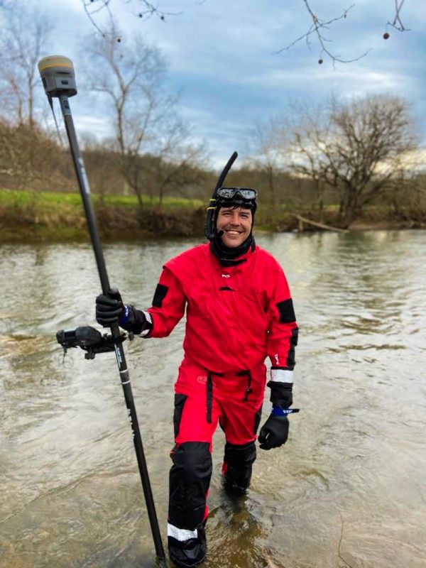 picture of engineer Zack Edwards in the stream with equipment